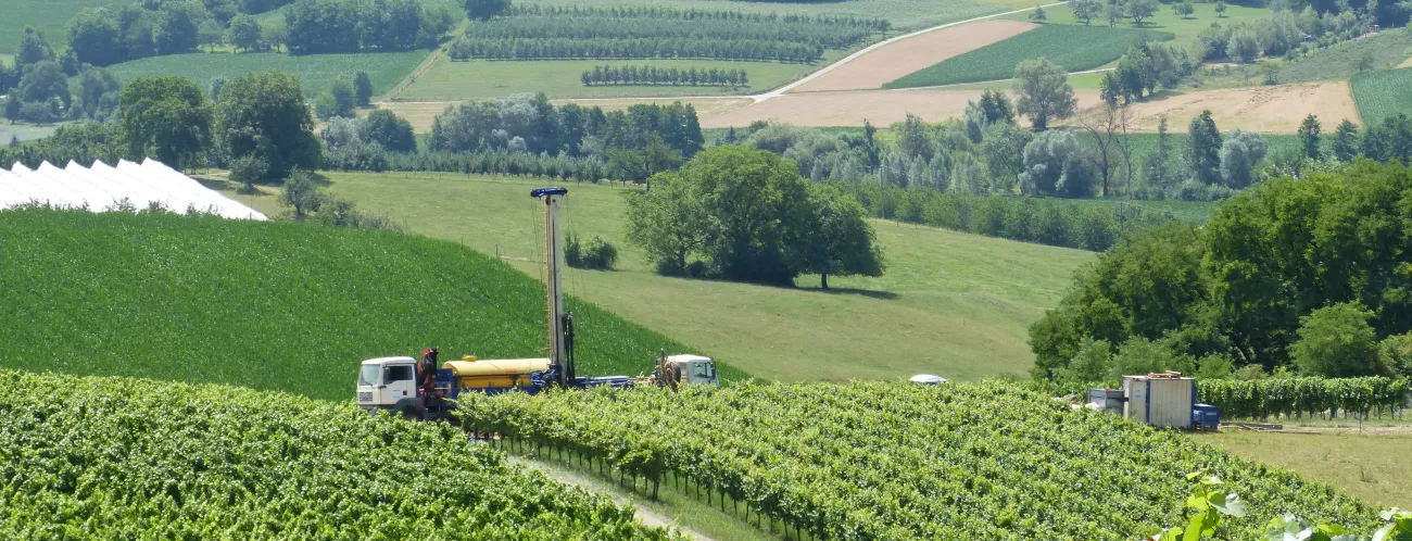 Ein LKW steht auf einem Weg in den Weinbergen und transportiert eine Bohranlage.