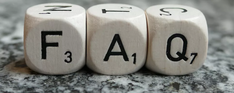 Auf polierten Stein liegen drei weiße Würfel mit den Buchstaben "F" "A" "Q"